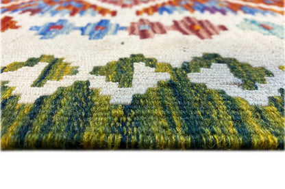 Close-up of the kilim rug: textured pile with green and cream-colored motifs