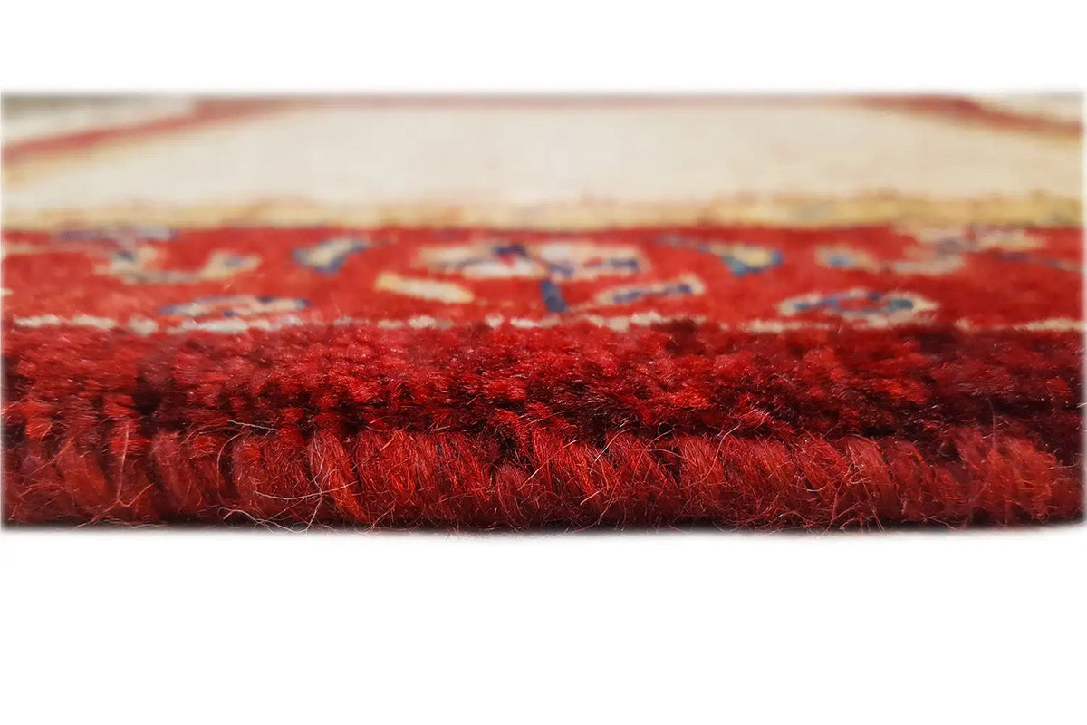 Carpet pile with a dense red texture and subtle color transitions, close-up side view.