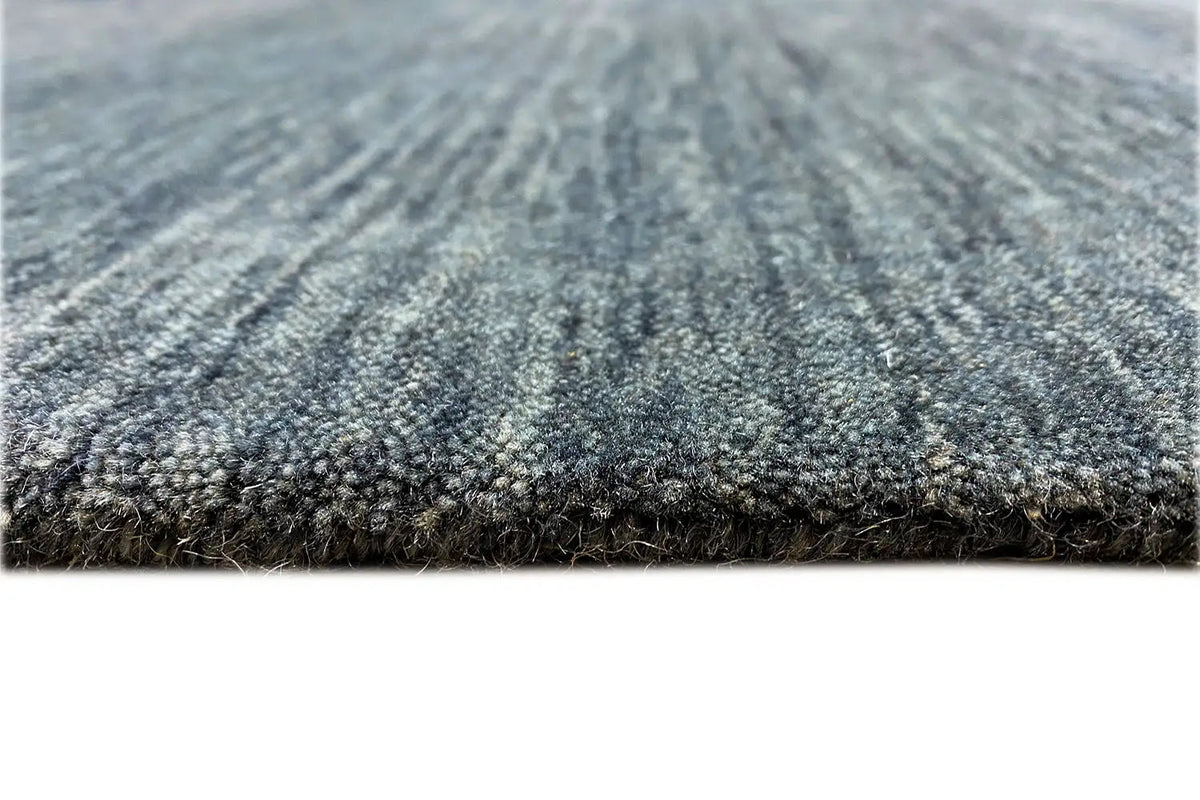Carpet surface in blue-gray with a mottled pattern and dense pile, close-up view