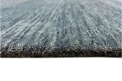 Carpet surface in blue-gray with a mottled pattern and dense pile, close-up view
