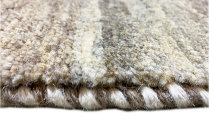 Gabbeh rug close-up showing the pile and fringes along the edge in light beige and gray tones