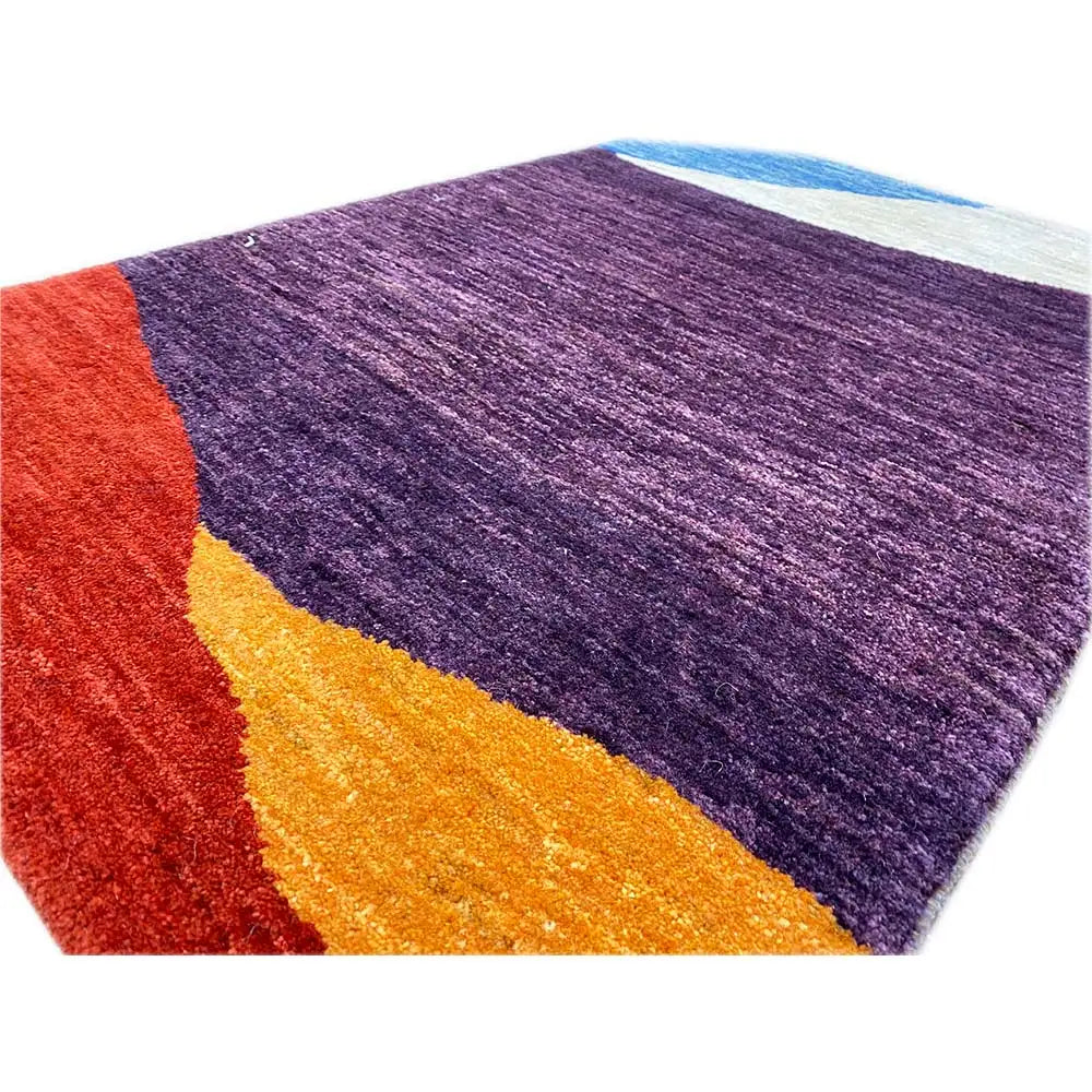 Close-up of a Gabbeh rug: dense pile in violet with yellow-orange and red accents