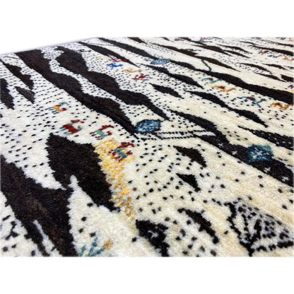 Close-up of a Gabbeh rug: dense stripe and dot pattern in cream, black, and blue