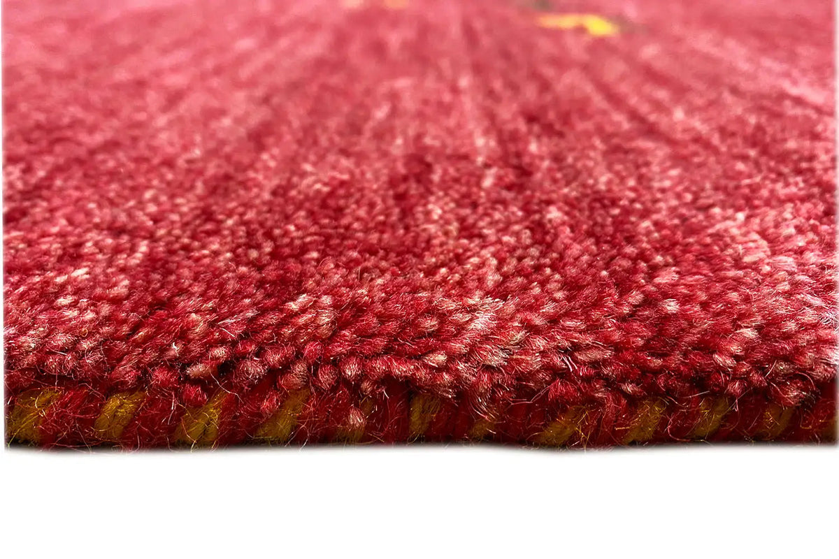 Red Gabbeh rug, detail of the dense pile and edge with fringe