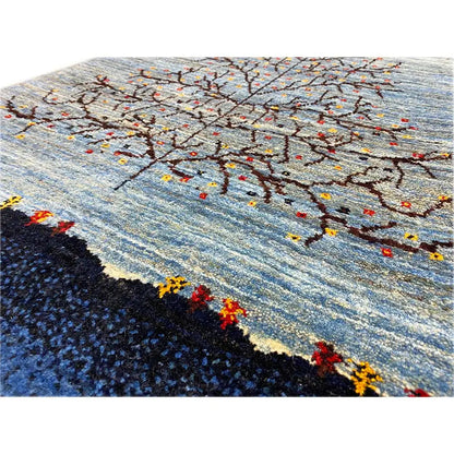 Detailed view of Gabbeh rug: tree branches in black, gray, and colorful dots on blue