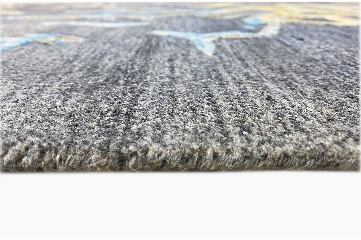 Hand-tufted rug in detail: short blue-gray pile with dense edge fringing