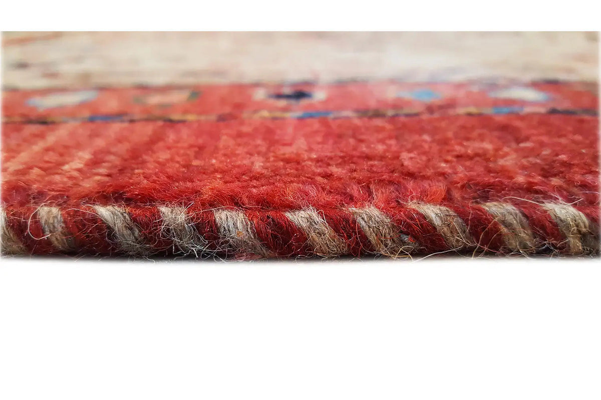 Carpet edge with short fringes, red binding, and beige pile.