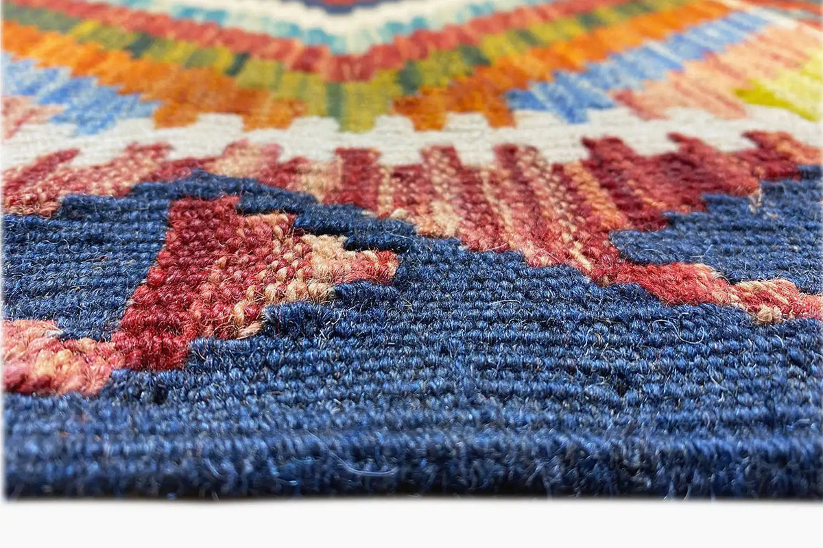 Close-up of a kilim runner: multicolored embroidered texture, blue border band, and reddish patterns