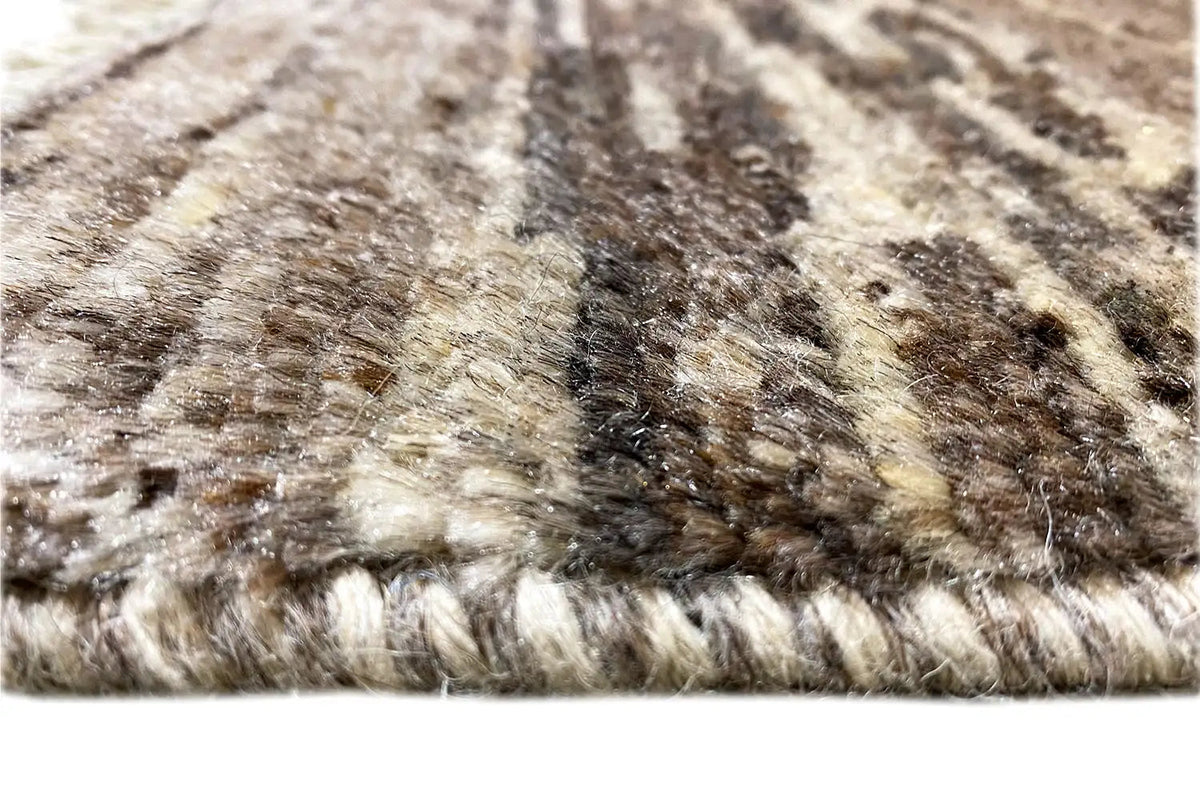 Rug surface with beige and dark brown fibers and fringes along the edge