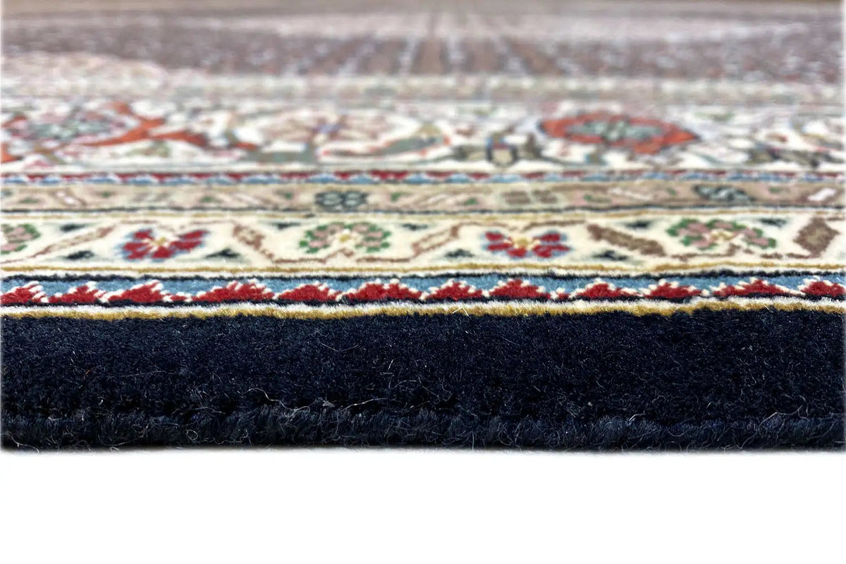 Tabriz-style rug with a border pattern around the edge and a dark pile underside