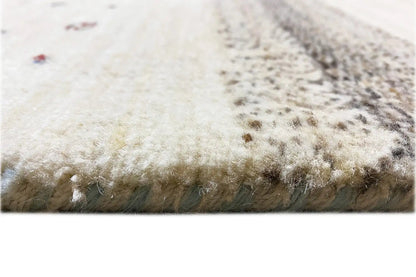 Close-up of a Gabbeh-Lori rug edge with short fringes, beige pile with colorful dots.