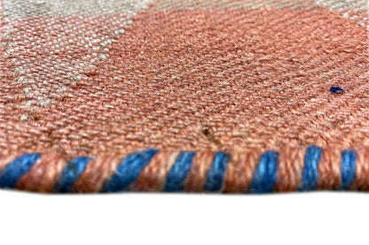 Carpet fabric with fringes in blue and rust, with a zigzag texture (detail)