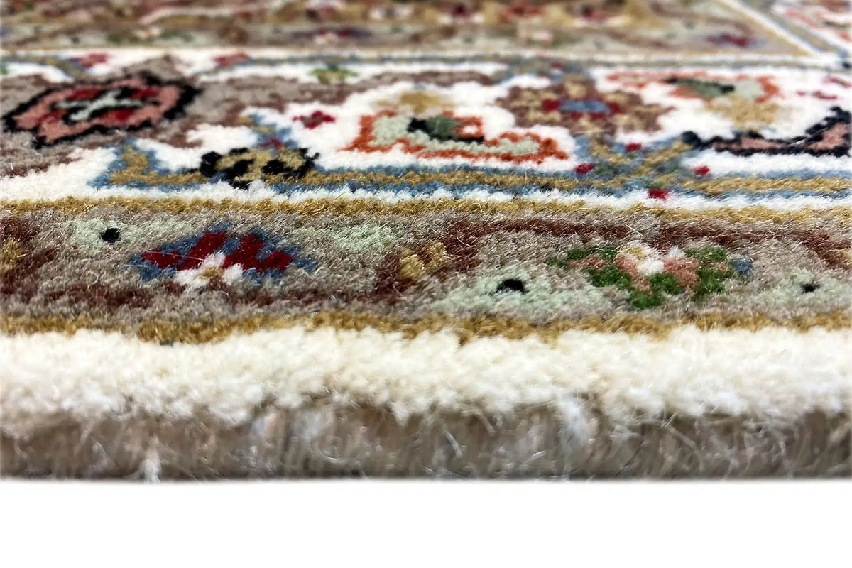 Indo Tabriz rug: Close-up of the pile and fringes at the edge of the rug, with a multicolored pattern.