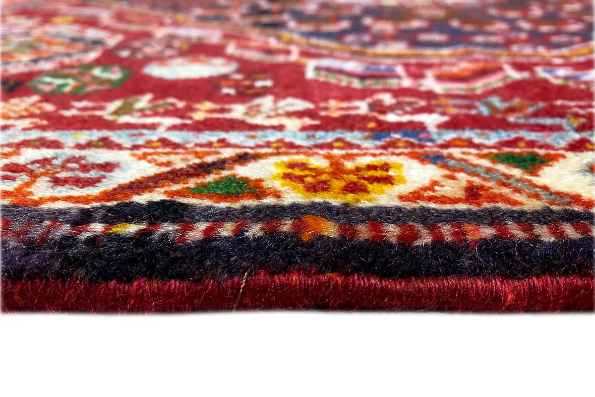 Close-up: carpet edge with fringes and a multicolored pattern on a red background