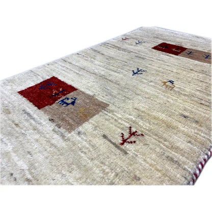 Gabbeh rug close-up: beige pile with a red motif field and blue ornament