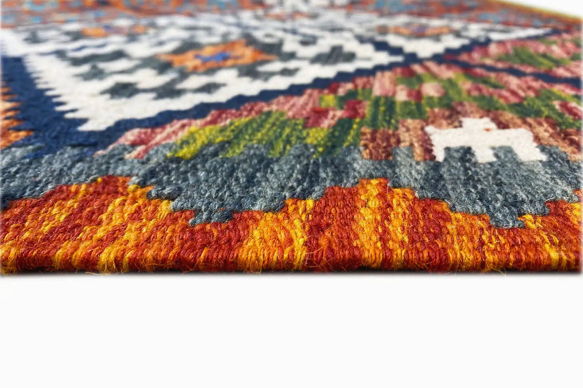 Close-up of the pile edge of a kilim rug with a colorful pattern and fringes.