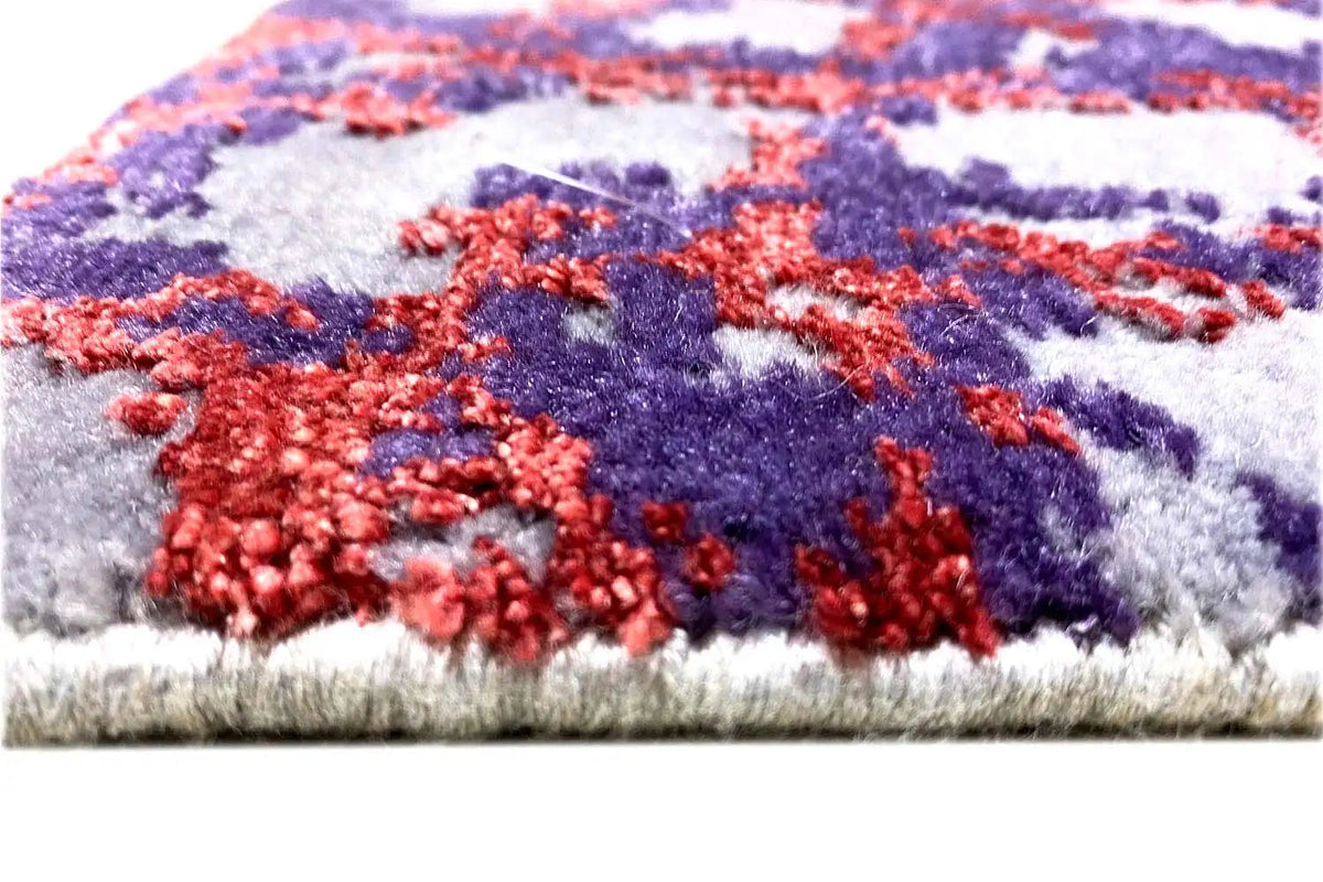 Rug edge with short pile; abstract pattern in blue, red, and purple.