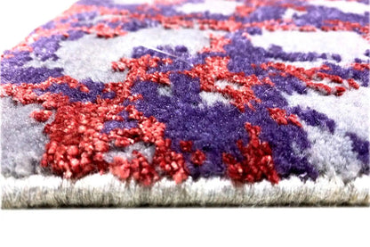 Rug edge with short pile; abstract pattern in blue, red, and purple.