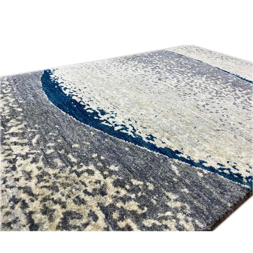 Close-up of Gabbeh rug: light beige texture with dark blue border and gray pattern