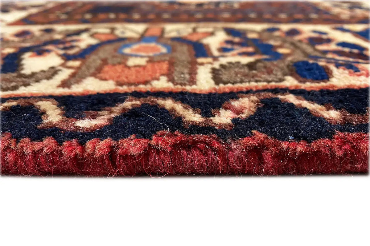 Bakhtiari rug close-up: reddish-brown pile and fringes along the edge