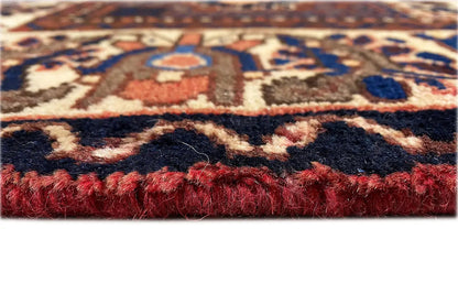 Bakhtiari rug close-up: reddish-brown pile and fringes along the edge
