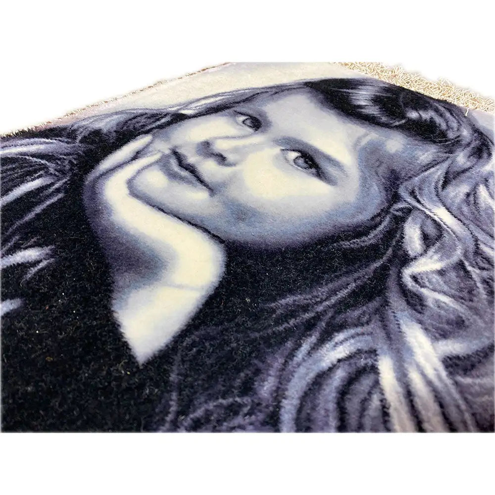 Close-up: tapestry with a portrait of a girl and fringe along the edge.