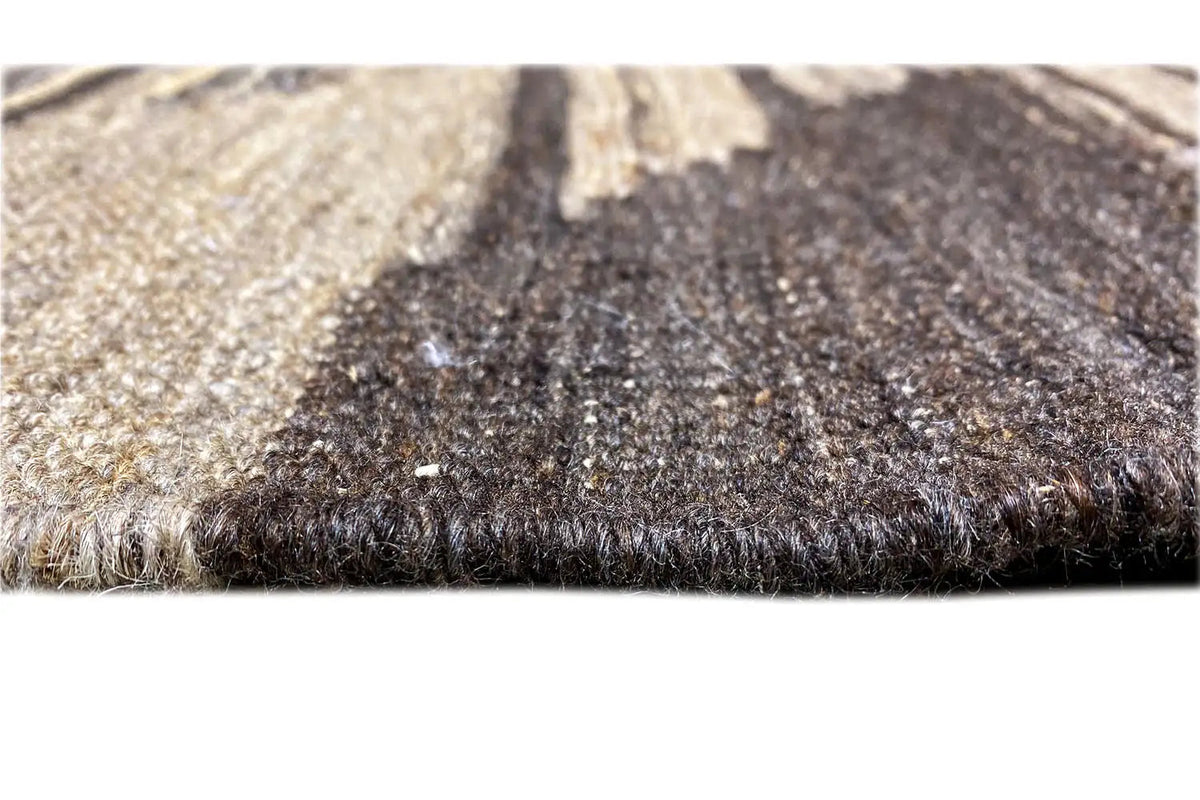 Kilim rug detail: dense pile and fringe along the edge, beige-gray with dark areas