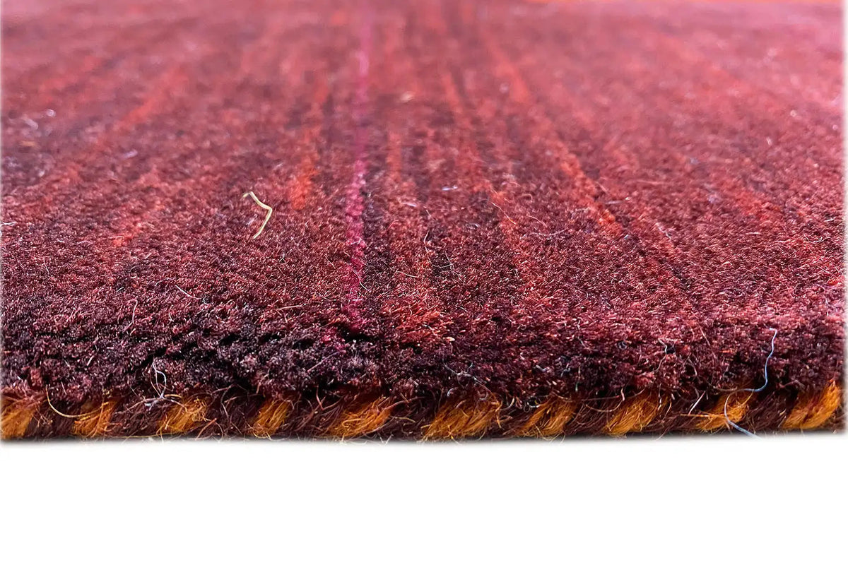 Gabbeh rug detail: dense dark red pile with an orange border