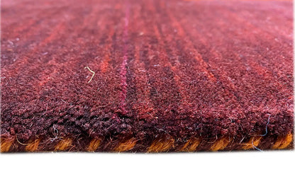 Gabbeh rug detail: dense dark red pile with an orange border