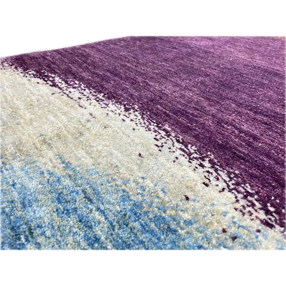 Close-up of a Gabbeh rug: purple and beige gradient with a blue, grainy pattern