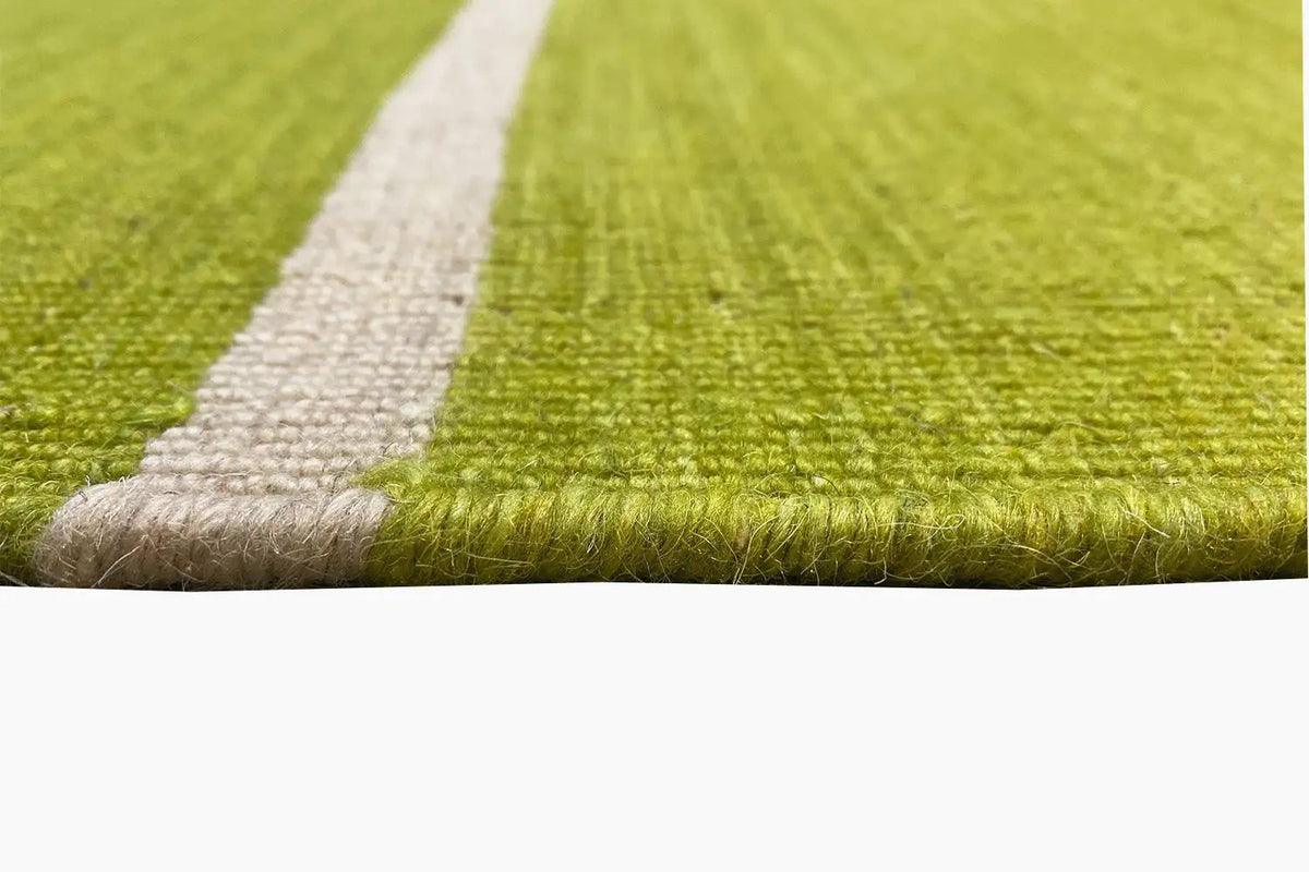 Carpet corner with a light-colored contrasting edge and fringe; green area with a white stripe