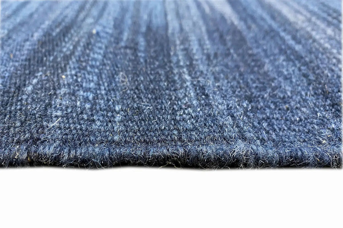 Close-up: blue kilim dhurrie with a dense weave and contrasting edge