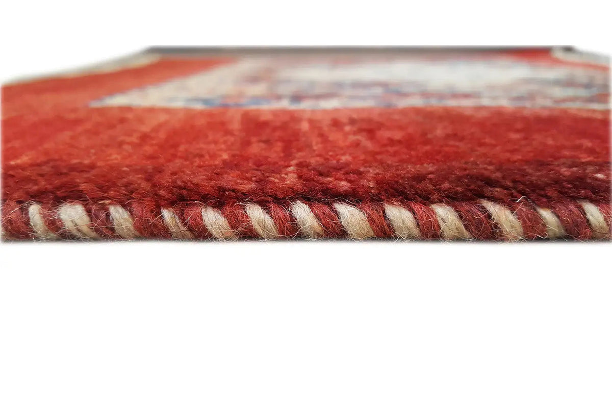 Close-up of a rug edge with twisted fringes and dense red pile