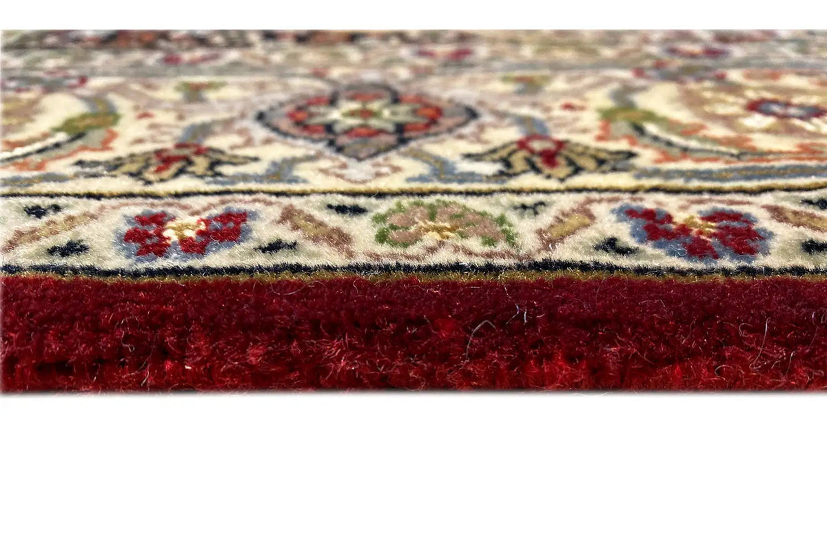 Rug edge with a dense red pile and fine pattern details along the border