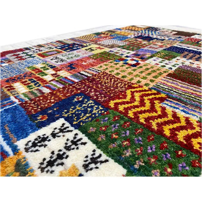 Gabbeh rug close-up: colorful square and floral motifs with a deep blue section