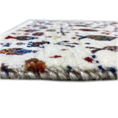 Gabbeh rug edge view with fringe, cream-colored, multicolored pattern.