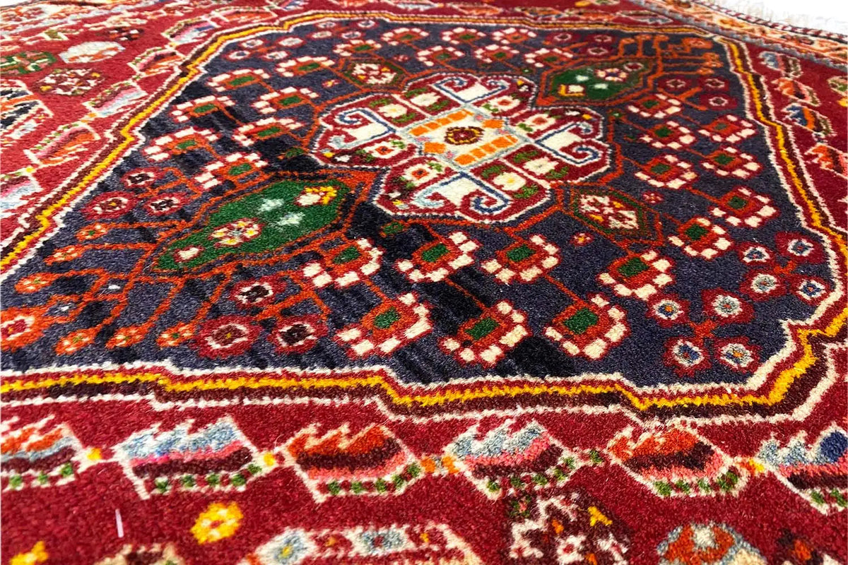 Close-up of a carpet with a geometric ornamental pattern in red, black and green