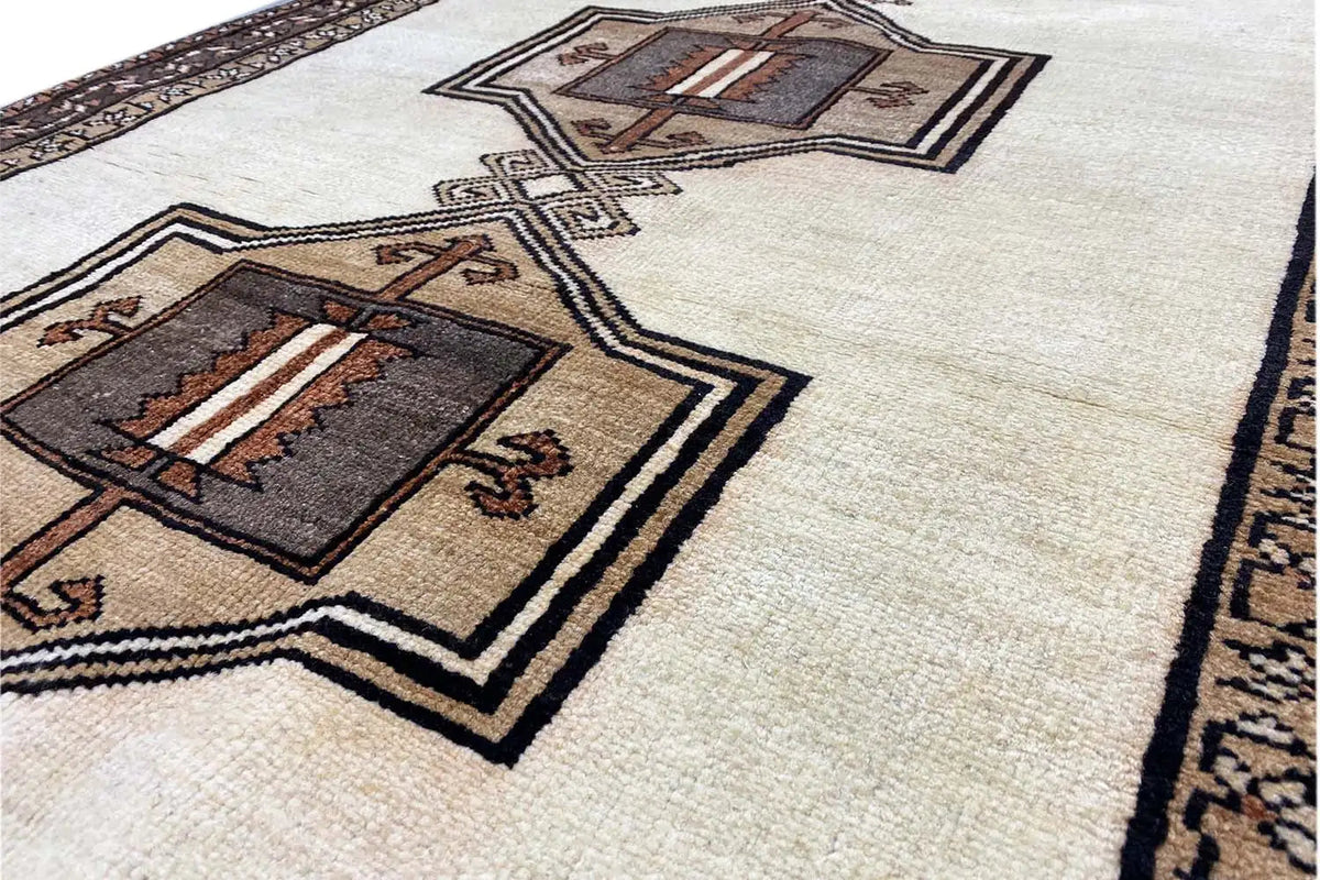 Detailed view: brown medallion with ornaments and a border on a beige background.