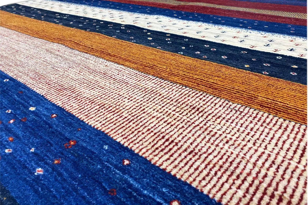 Close-up of a Gabbeh rug: woven stripes in blue, red, and brown with fine dots