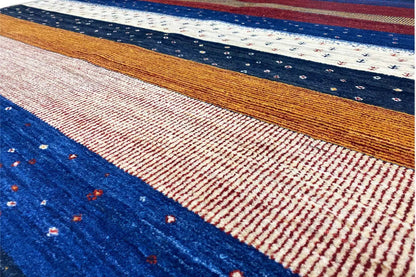 Close-up of a Gabbeh rug: woven stripes in blue, red, and brown with fine dots