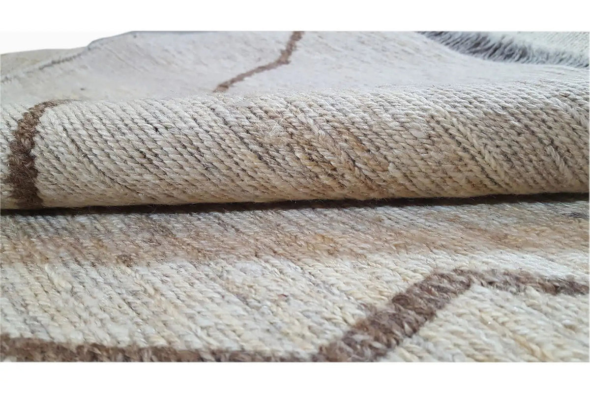 Close-up of the woven texture of a kilim rug, beige material with brown and gray discoloration