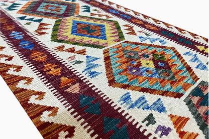 Kilim runner detail with colorful diamonds, decorative trim, and a densely woven texture