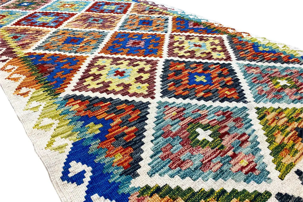 Close-up: geometric diamonds made of colorful threads on a light Afghan rug, detailed