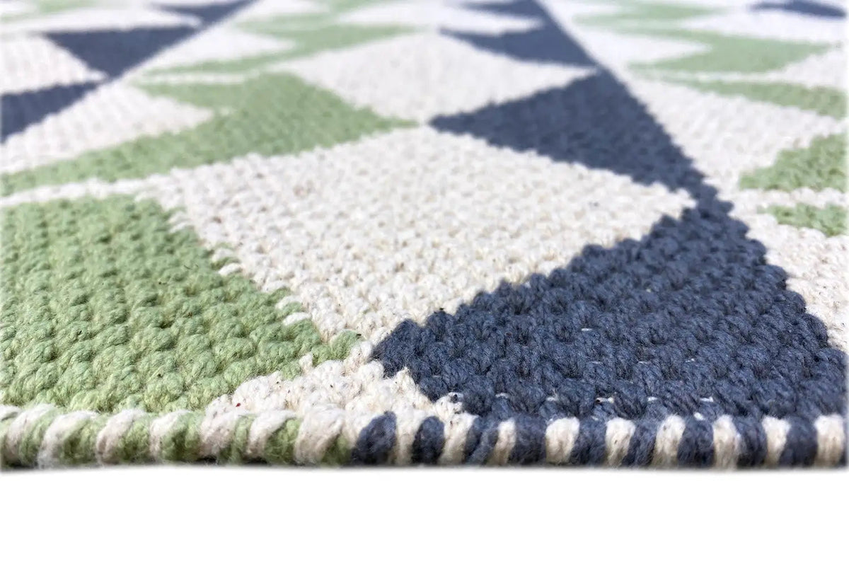 Close-up of a kilim rug: woven texture with contrasting bands in green, blue, and white