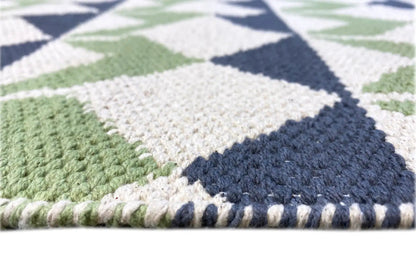 Close-up of a kilim rug: woven texture with contrasting bands in green, blue, and white