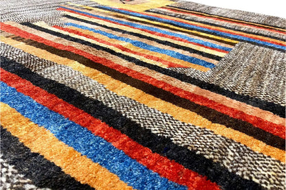 Carpet detail with colorful stripes in blue, red, and yellow on a gray background.