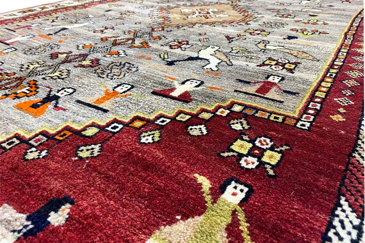 Gabbeh rug detail: red-gray pile with figures, ornaments, and a zigzag border
