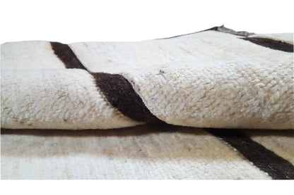 Gabbeh rug detail: beige pile with dark stripes and a knotted surface
