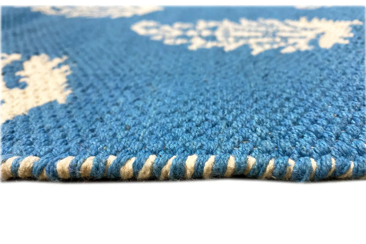 Blue kilim texture with a frayed edge; tightly woven stitches in detail.