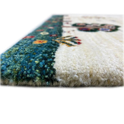 Gabbeh rug detail view: beige pile with a dark green patterned stripe and dense wool texture.